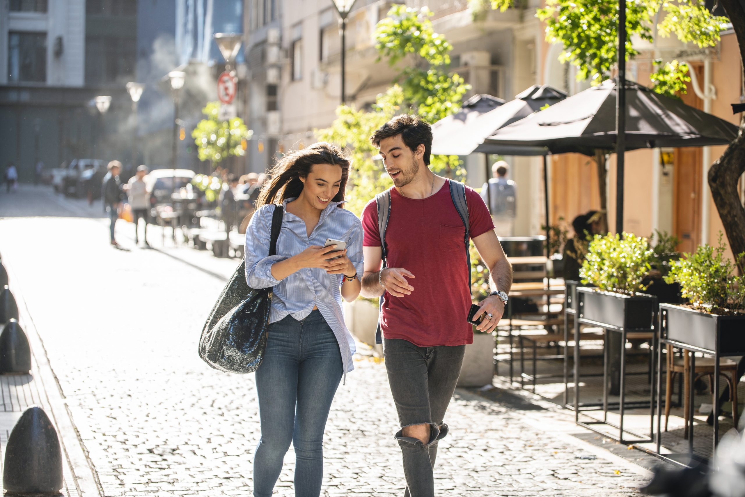 Young Couple Walking and Looking at Phone scaled